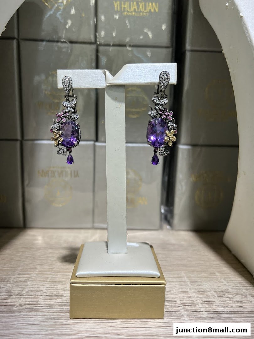 Exquisite amethyst and diamond earrings displayed on a jewelry stand, with branded boxes in the background.