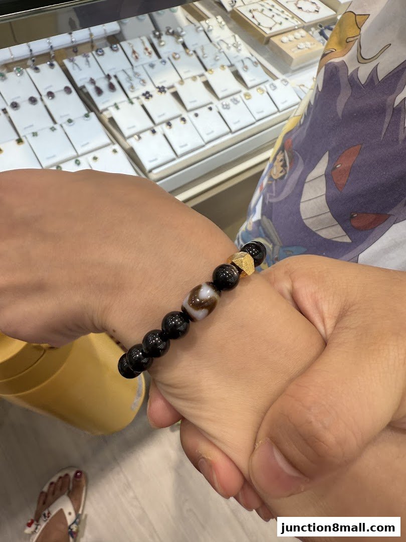 A close-up of a bracelet with black beads and a patterned bead on a person's wrist.