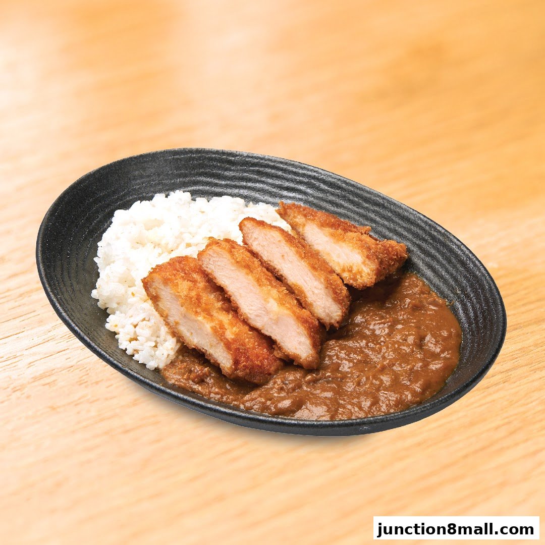 A black oval plate filled with white rice and sliced katsu chicken served with curry.