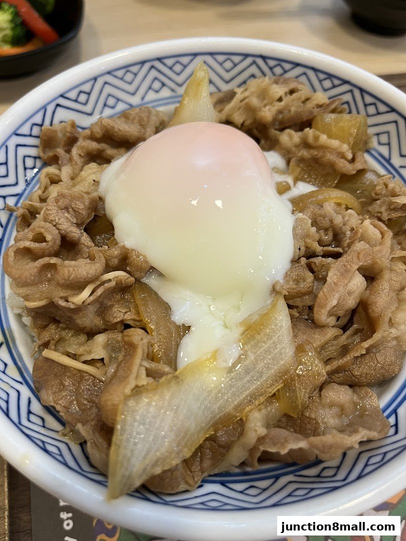 A close-up of a Yoshinoya beef bowl topped with a soft-boiled egg.