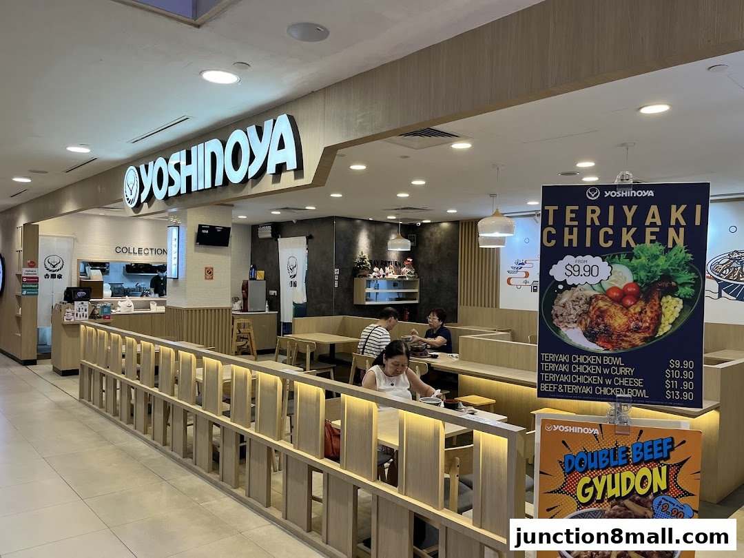 Interior view of Yoshinoya restaurant with customers dining and promotional posters.