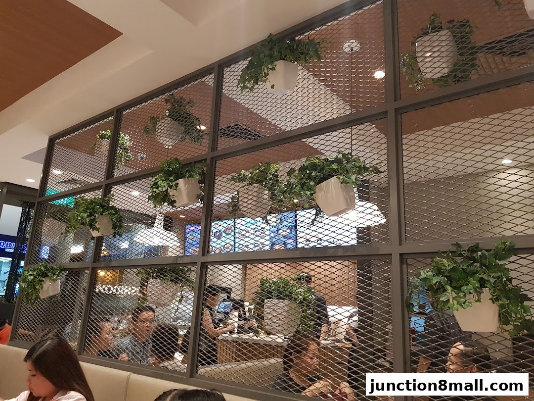 Interior view of a Yoshinoya restaurant with hanging plants and diners.