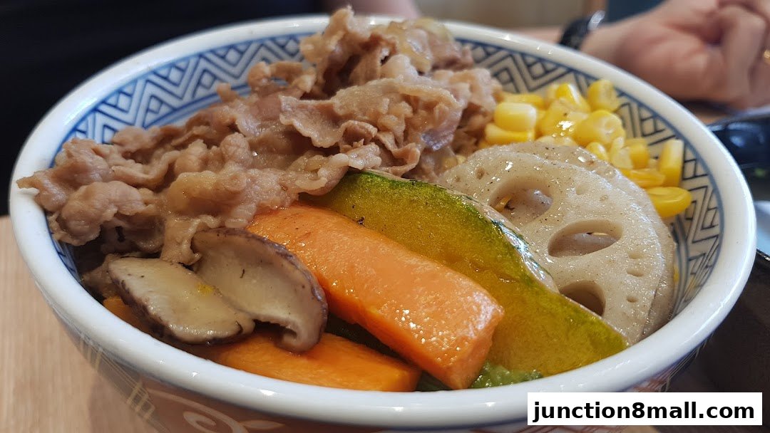 A close-up of a Yoshinoya bowl filled with beef, vegetables, and corn.