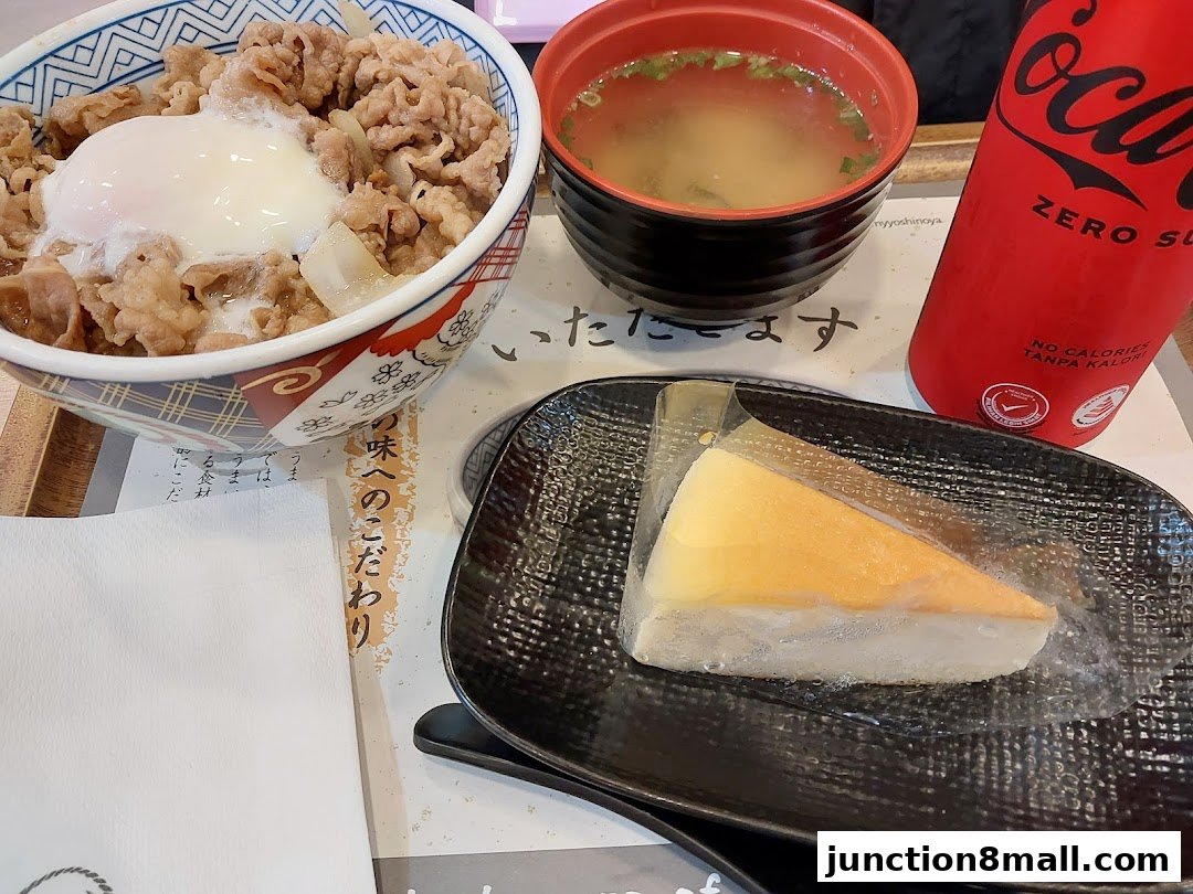 A Yoshinoya meal featuring beef bowl, miso soup, Coca-Cola Zero, and a slice of cheesecake.