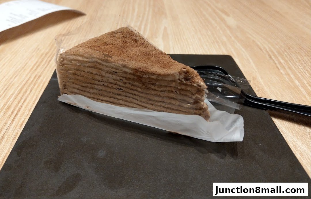 A slice of layered chocolate cake dusted with cocoa powder, served with a fork.
