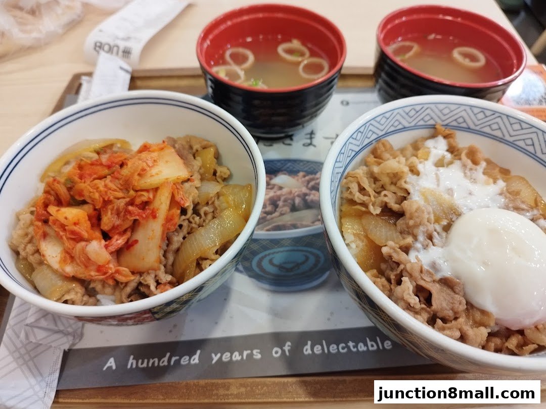 Two bowls of Yoshinoya's signature beef bowls with kimchi and a soft-boiled egg, served with soup.