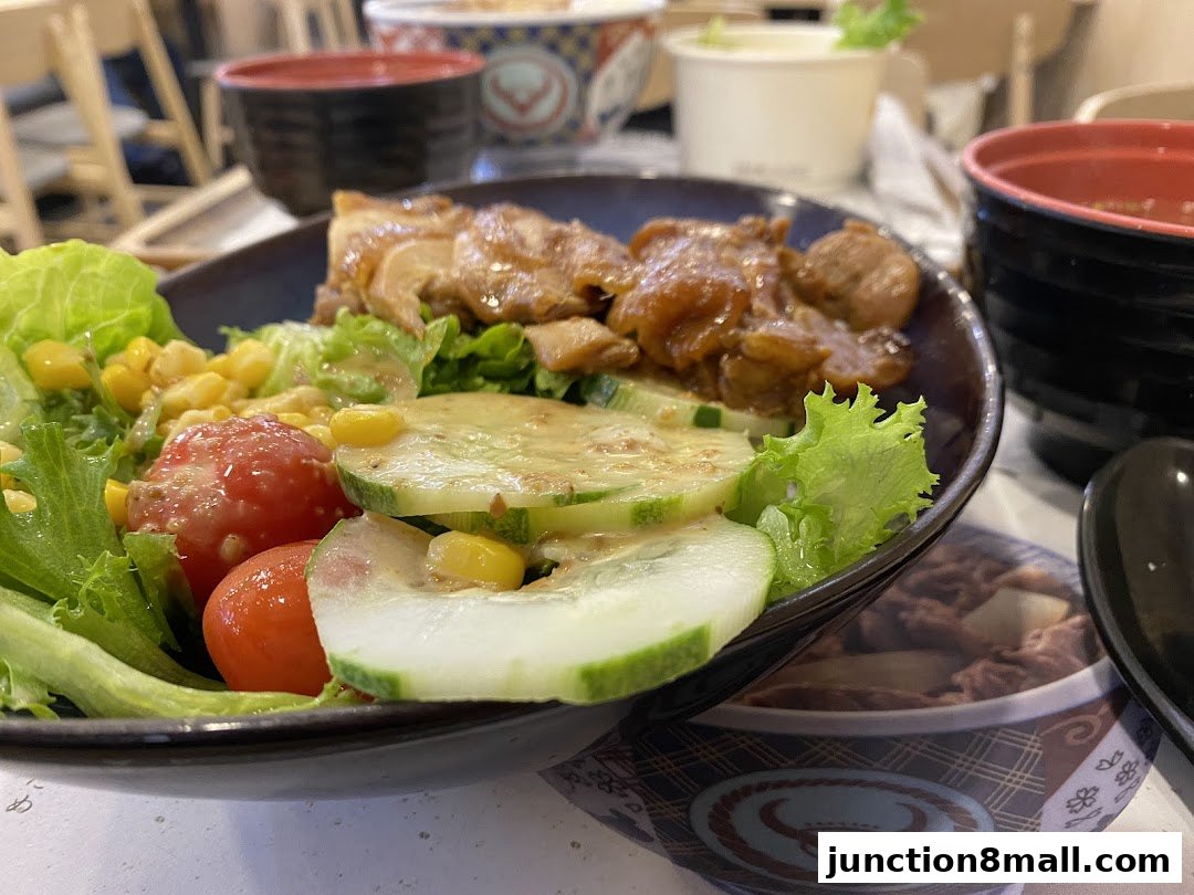 A close-up of a Yoshinoya salad with chicken, corn, tomatoes, and cucumbers.