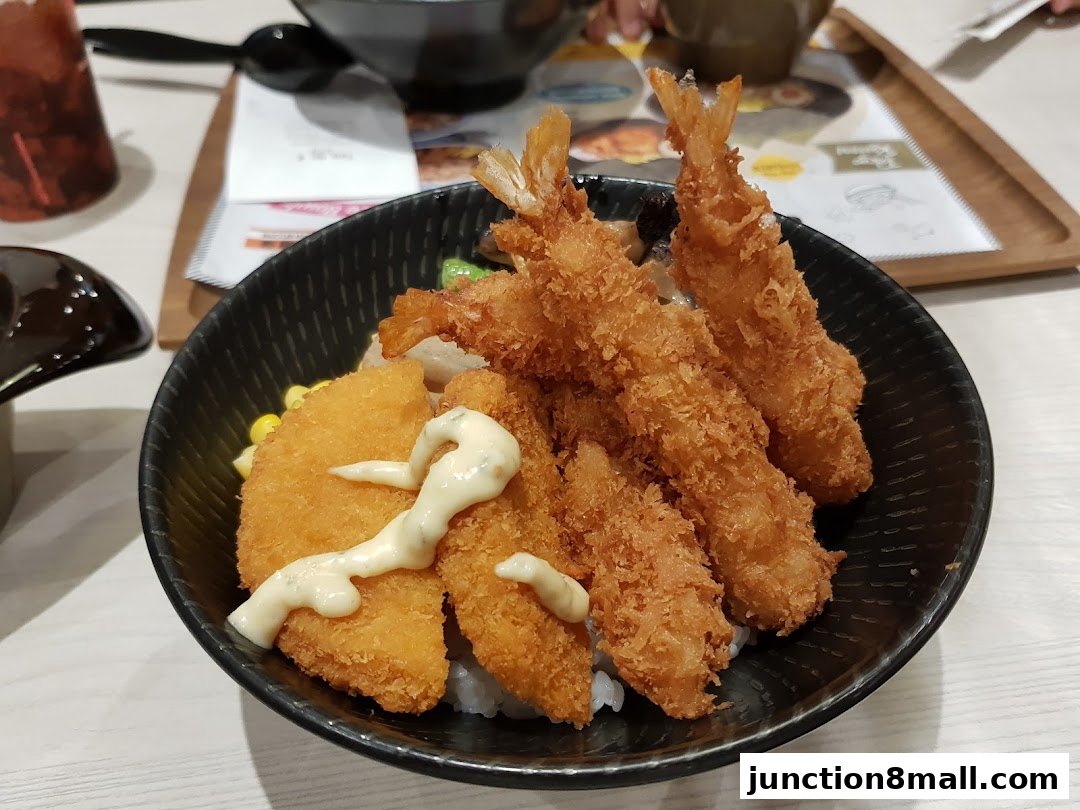A close-up of a Japanese rice bowl with fried shrimp and fish.